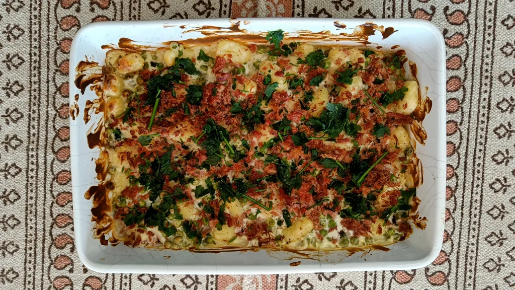 Photograph of Baked gnocchi with crispy ham hock & peas.