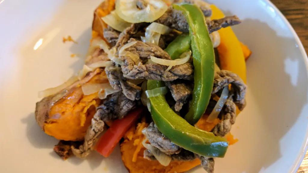 Photograph of Baked sweet potatoes with steak fajita filling.