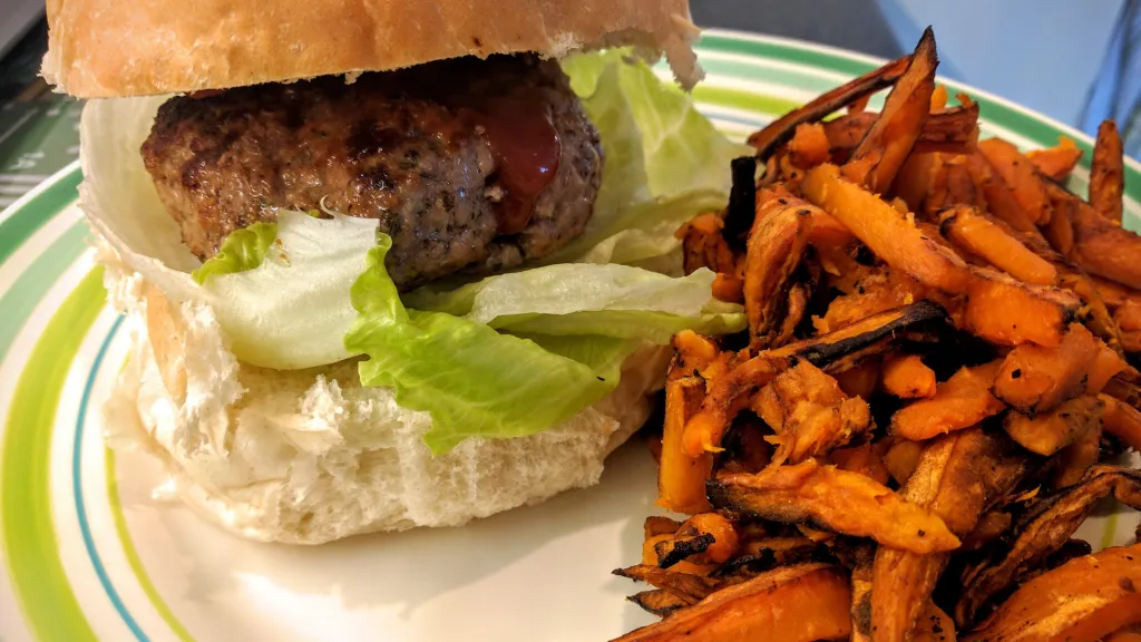 Photograph of Herby lamb burgers with sweet potato fries.