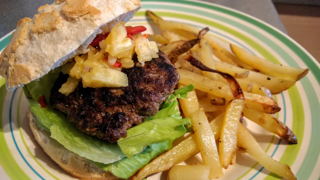 Photograph of Jerk beefburger with pineapple relish & chips.