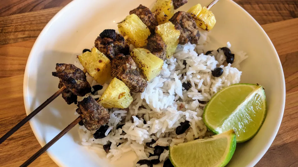 Photograph of Jerk pork & pineapple skewers with black beans & rice.