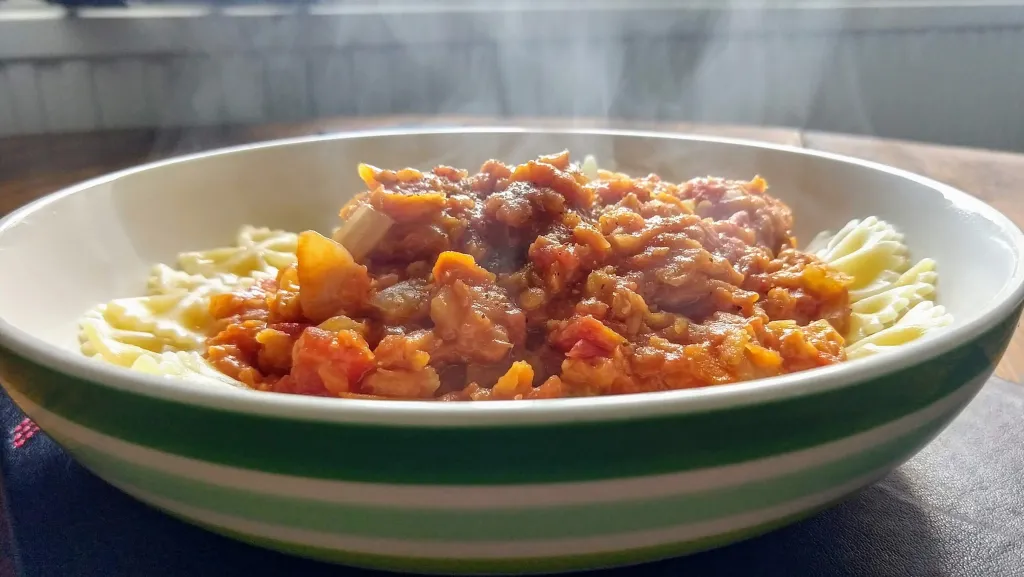 Photograph of Lentil bolognaise with parmesan basil and pine nuts.