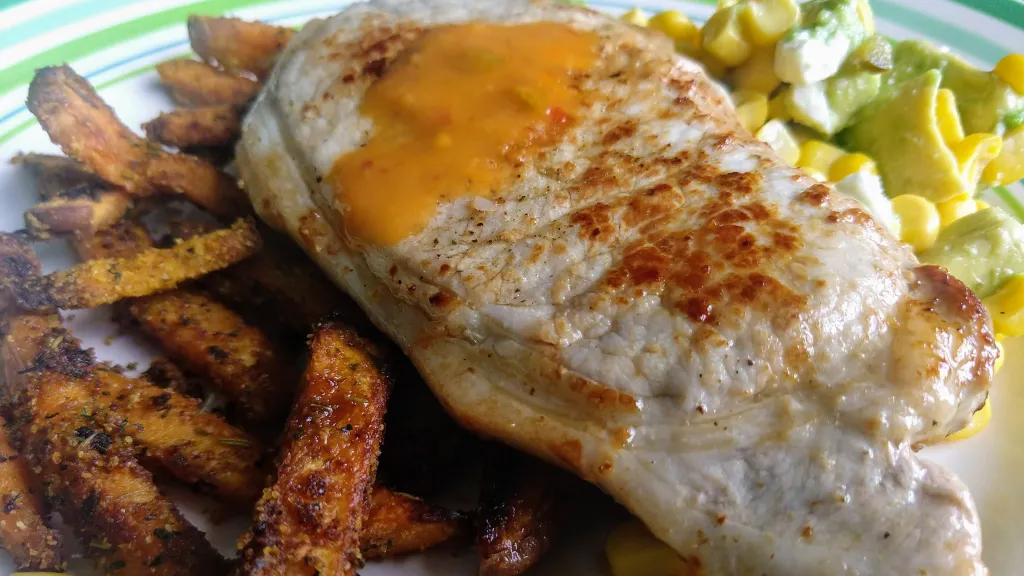 Photograph of Peri peri pork with sweet potato wedges and sweetcorn salsa.