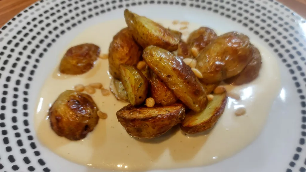 Photograph of Roasted potatoes with aïoli and buttered pine nuts.