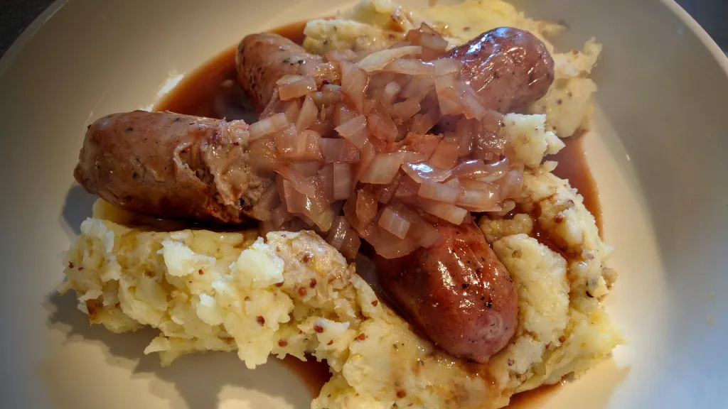 Photograph of Sausages & mash with cumberland sauce.