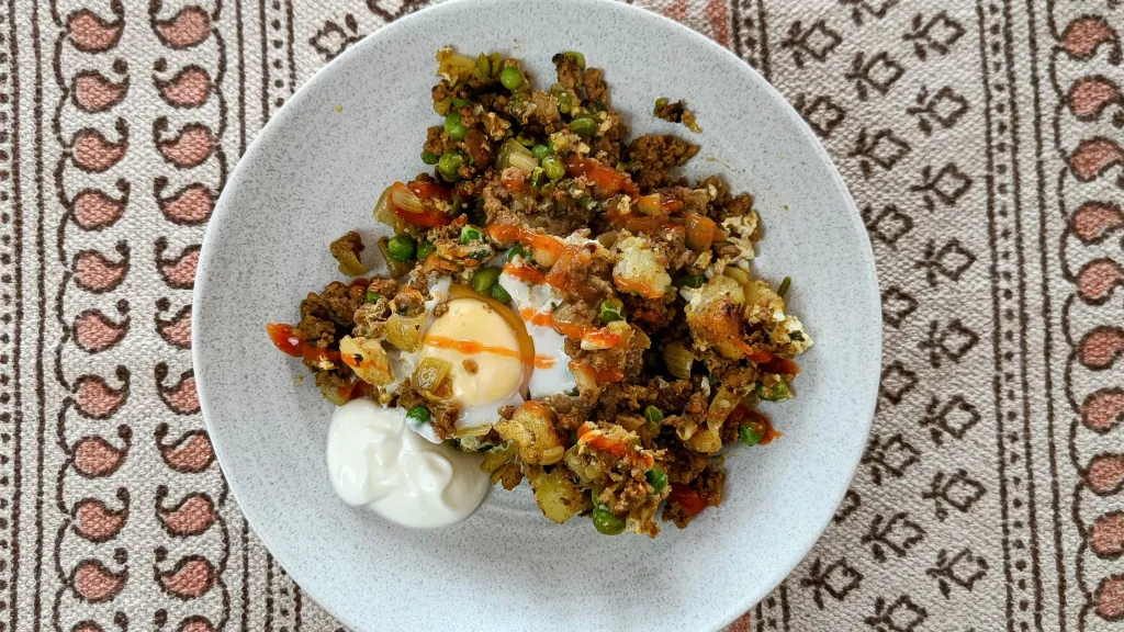 Photograph of Smoky beef, potato & pea pan-fry with eggs & yogurt.