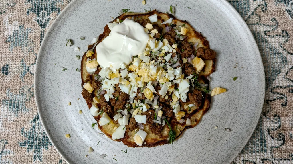 Photograph of Spiced beef pancakes with chopped egg, dill & crème fraîche.