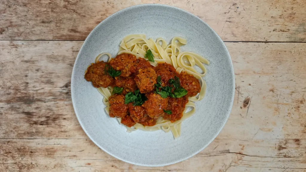 Photograph of Spicy bulgur wheat meatballs in garlicky tomato sauce.