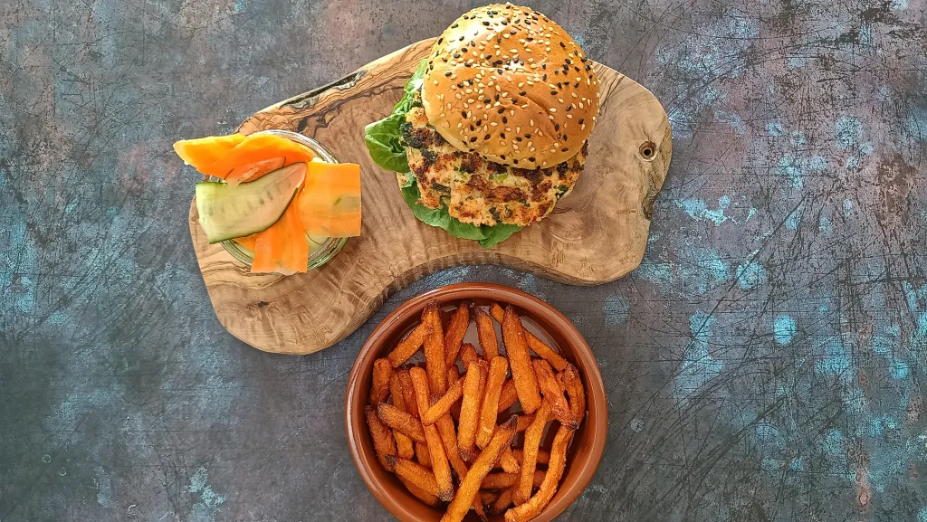Photograph of Spicy salmon burgers with sriracha mayo & pickles.