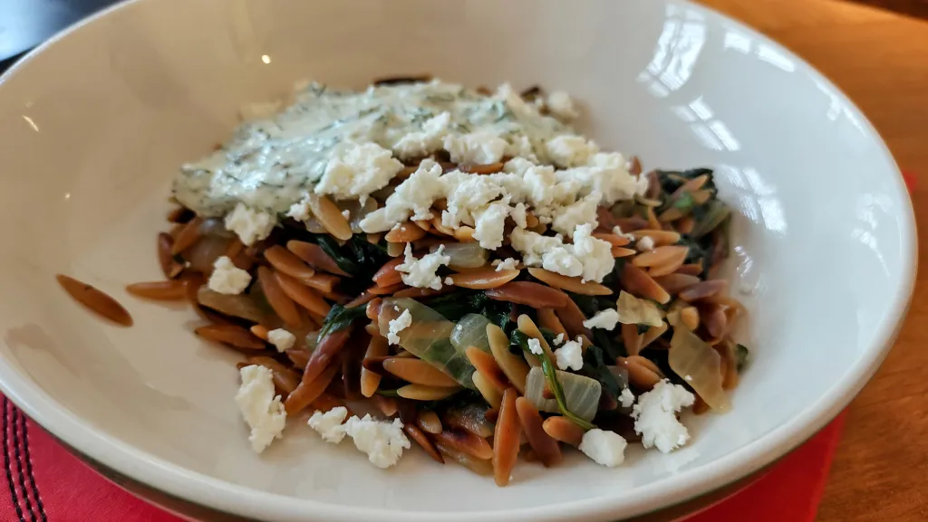 Photograph of Spinach and toasted orzo, with dill and green chilli salsa.