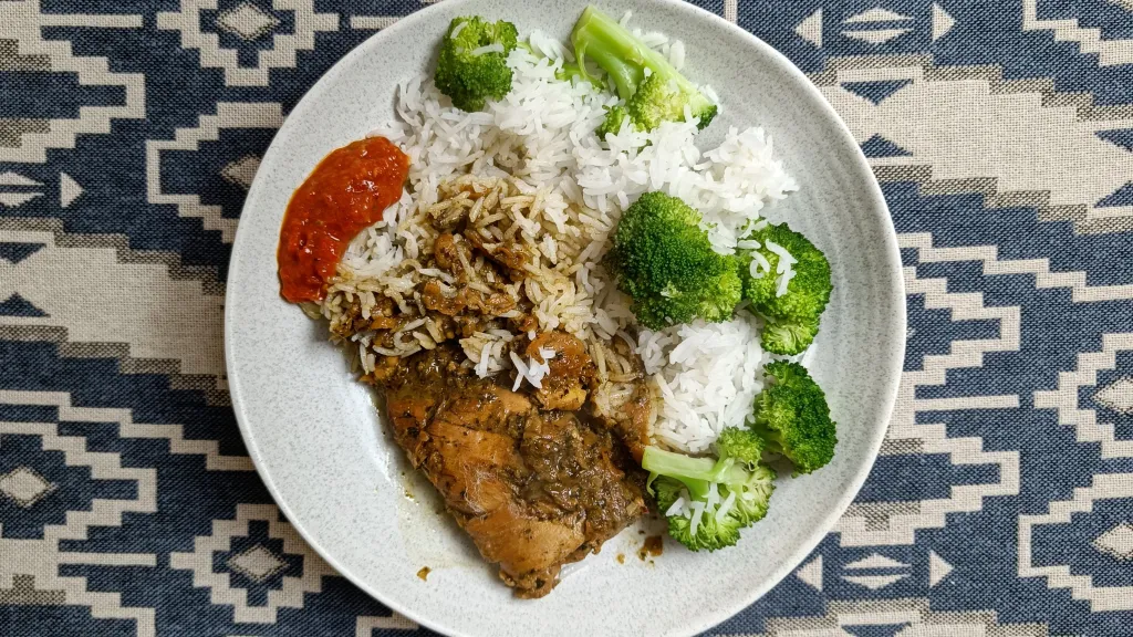 Photograph of Trini brown stew chicken with hot pepper sauce.