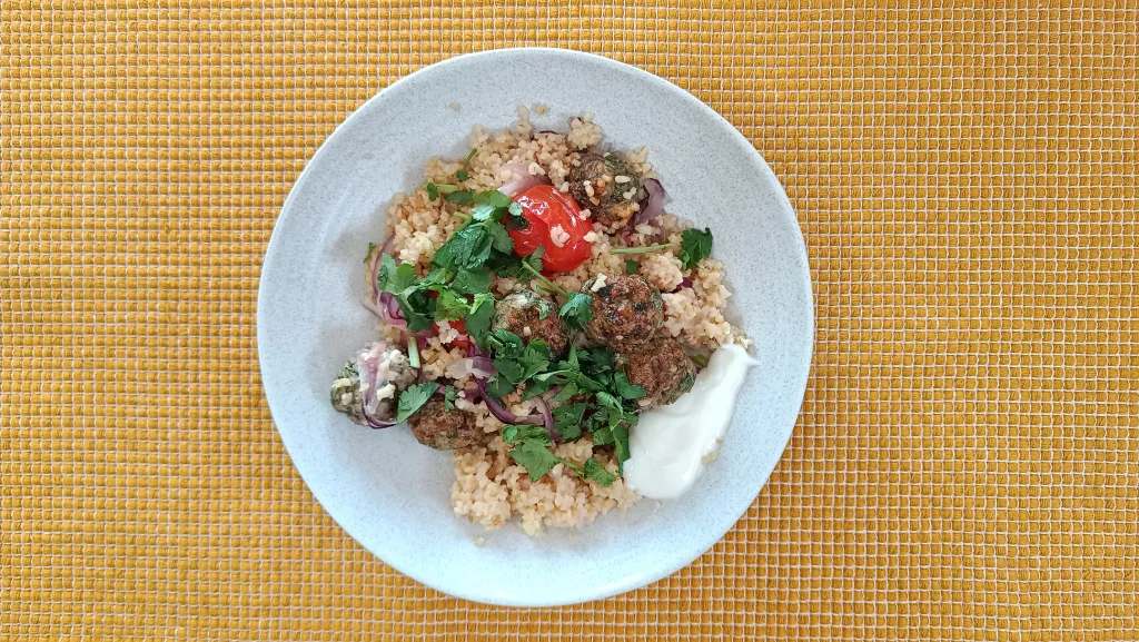 Photograph of Za’atar spiced meatballs with tomatoes & bulgur.